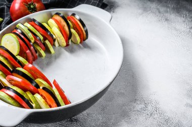 Ratatouille pişirme - geleneksel Fransız Provenkal sebze yemeği. Gri arka plan. Üst Manzara. Boşluğu kopyala.