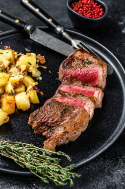 Kızarmış biftek, patates ve sığır eti. Siyah arka plan. Üst görünüm.