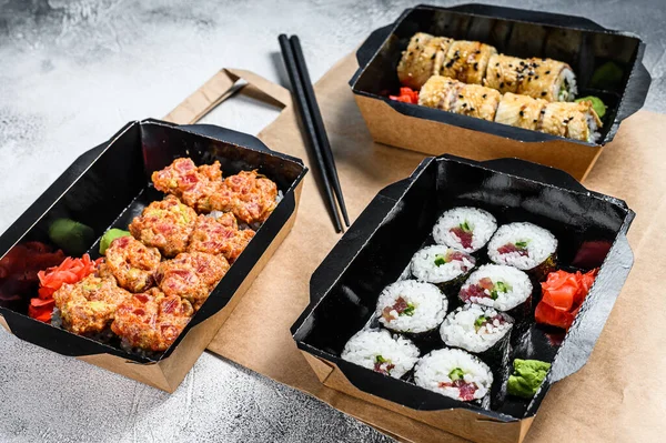 The sushi rolls in the delivery package, ordered in sushi take-out restaurant. Gray background. Top view.