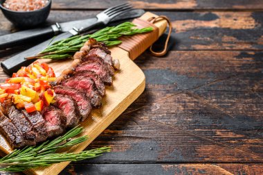 Izgara sığır filetosu ya da kesme tahtasının üzerinde otlarla birlikte picanha bifteği. Koyu ahşap arka plan. Üst Manzara. Boşluğu kopyala.