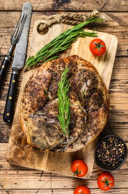 Kesme tahtasında kızarmış domuz jambonu. Saplanmış et. Ahşap arka plan. Üst görünüm.