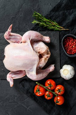 Bütün tavuğu biberiye ve pembe biberle pişirme fikri. Siyah arka plan. Üst görünüm.