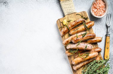 Kesme tahtasında ızgara sosis ve şifalı bitkiler. Beyaz arka plan. Üst Manzara. Boşluğu kopyala.