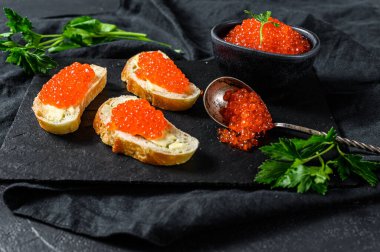 Kasede kırmızı havyar ve taş tahtada sandviç. Siyah arka plan. Üst görünüm.