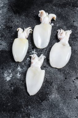 Masada çiğ küçük mürekkep balığı var. Siyah arka plan. Üst görünüm.