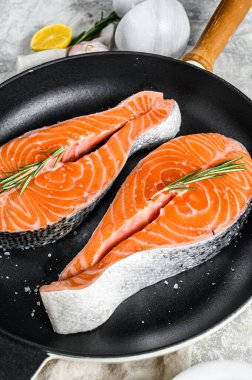 Kızartma tavasında çiğ somon bifteği. Sağlıklı deniz ürünleri. Gri arka plan. Üst görünüm.