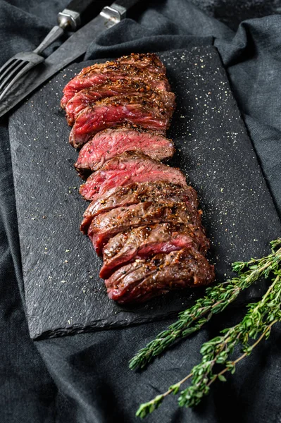 Grilled roasting rare sliced top blade, Denver steak. Marble meat beef. Black background. Top view.