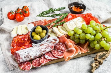 İtalyan antipasto, jambon, parma, keçi peyniri, zeytin ve üzümlü ahşap kesim tahtası. Antipasti. Gri arka plan. Üst görünüm.