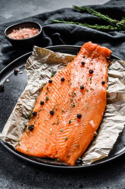 Taze somon fileto, tuz, bitki ve baharatlı. Siyah arka plan. Üst görünüm.