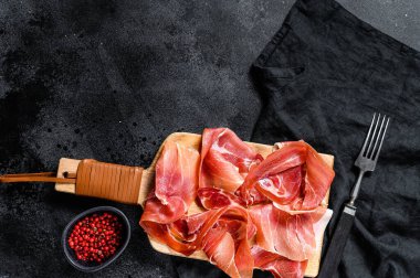 İspanyol jamonu Serrano, jambon. Siyah arkaplan, üst görünüm, metin için boşluk.