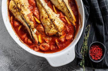 Fırın kabında domateslerde pişirilmiş maymunbalığı. Siyah arka plan. Üst görünüm.