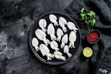 Biberiye ve maydanozlu taze mürekkep balığı. Siyah arka plan. Üst görünüm.