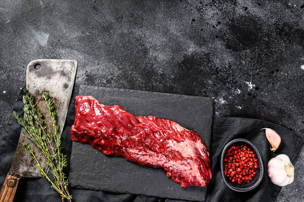 Raw marbled beef steak with pink pepper and thyme. Black background. Top view. Copy space.