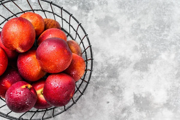 Fresh red nectarines in a steel basket. Gray background. Top view. Copy space.
