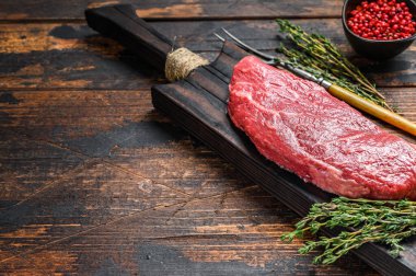 Kesme tahtasındaki çiğ Striploin bifteği, mermer sığır eti. Karanlık ahşap arka plan. Üst Manzara. Boşluğu kopyala.