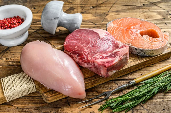 Animal protein sources meat, fish, and poultry. Raw steaks. wooden background. Top view.