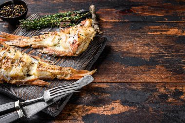 Izgara Kızıl Deniz levreği ya da orfoz. Koyu ahşap arka plan. Üst Manzara. Boşluğu kopyala.