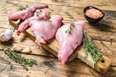 Kesme tahtasında çiğ tavşan bacağı. Ahşap arka plan. Üst görünüm.