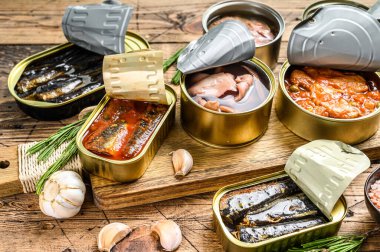 Açılmış kutular saury, somon, sprat, sardalya, kalamar ve ton balığıyla korunur. Ahşap arka plan. Üst görünüm.