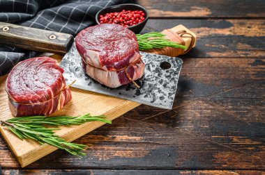 Kesme tahtasının üzerinde çiğ biftek fileto fileto. Karanlık ahşap arka plan. Üst Manzara. Boşluğu kopyala.