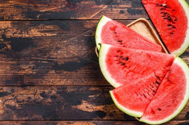 Bir yığın taze kırmızı dilimlenmiş karpuz. Karanlık ahşap arka plan. Üst Manzara. Boşluğu kopyala.