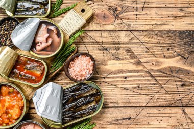Açılmış kutular saury, somon, sprat, sardalya, kalamar ve ton balığıyla korunur. Ahşap arka plan. Üst Manzara. Boşluğu kopyala.