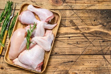 Tahta tepside taze çiğ tavuk eti, kanat, göğüs, but ve but. Ahşap arka plan. Üst Manzara. Boşluğu kopyala.