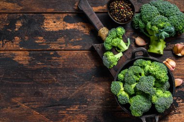 Kevgir soslu çiğ yeşil brokoli. Koyu ahşap arka plan. Üst Manzara. Boşluğu kopyala.