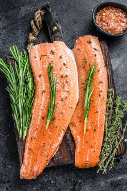 Tuzlu somon ya da baharatlı ve otlu alabalık filetosu. Siyah ahşap arka plan. Üst görünüm.