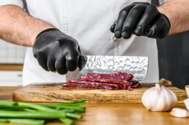 Adam çiğ et kesiyor. Siyah eldivenli bir şef. Etli tartar pişirme kavramı.