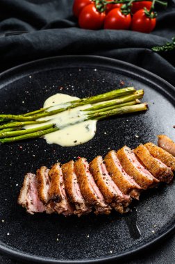 Karamelli kuşkonmaz ile sulu ördek göğsü bifteği. Siyah arka plan. Üst görünüm.