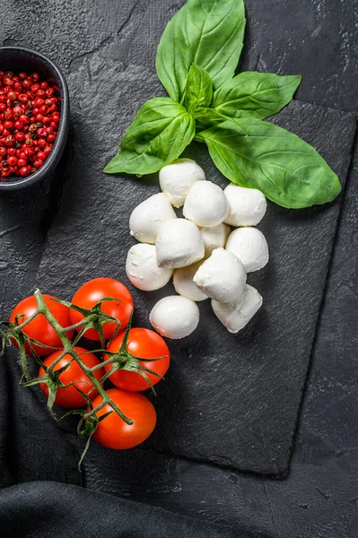 Caprese salatası, mini mozzarella peyniri, fesleğen yaprağı ve vişneli domates. Siyah arka plan. en üstteki görünüm.