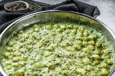 Pesto soslu patates gnocchi, parmesan peyniri ve ıspanak. İtalyan makarnası. gri arka plan. Üst görünüm.