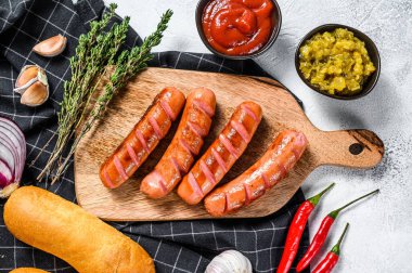 Ev yapımı sosisli sandviç yapmak için gerekli malzemeler. Sosis, taze pişmiş çörek, hardal, ketçap, salatalık. Beyaz arka plan. Üst görünüm.