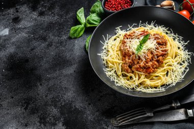 Domatesli spagetti bolonez makarna ve kıyma, parmesan peyniri ve fesleğen. Siyah arka plan. Üst Manzara. Boşluğu kopyala.