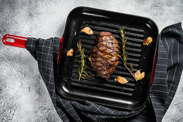 Grilled Top Blade steak on a grill pan, marbled beef. Gray background. Top view.