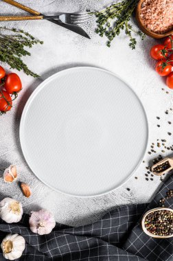 Taze çiğ sebze ve sebzelerin ortasında beyaz boş bir tabak. Sağlıklı, temiz yemek, vejetaryen, diyet yemek konsepti. Beyaz arka plan. Üst Manzara. Boşluğu kopyala.