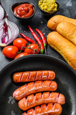 Farklı ev yapımı sosisli sandviçler, kızarmış soğan, acı biber, domates, ketçap, salatalık ve sosis. Siyah arka plan. Üst görünüm.