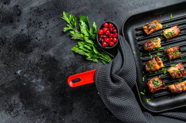 Tavaya sarılmış pastırmalı tavuk göğsü. Siyah arka plan. Üst Manzara. Boşluğu kopyala.