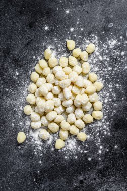 Siyah kesme tahtasında pişmemiş ev yapımı gnocchi. Siyah arka plan. Üst görünüm.