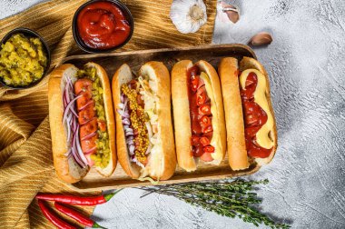 Tepside çeşitli malzemelerle dolu sosisliler. Domuz ve sığır etli sosisli nefis sosisler. Beyaz arka plan. Üst görünüm