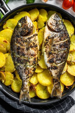 Tavada patates ile ızgara Dorado balığı. Gri arka plan. en üstteki görünüm