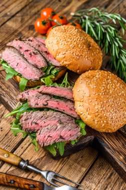 Biftek dilimli hamburger, roka ve ıspanak. Ahşap arka plan. Üst görünüm.