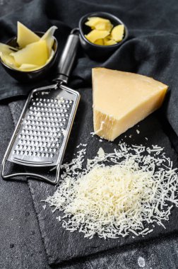 İtalyan sert parmesan peyniri dilimi, kesilmiş, rendelenmiş. Siyah arka plan. Üst görünüm.