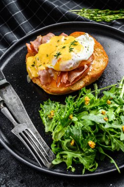 Pastırmalı kahvaltı burgeri, Benedict yumurtası, brioche ekmeğine Hollandaise sosu. Siyah arka plan. Üst görünüm.