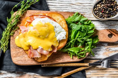 Pastırmalı kahvaltı burgeri, Benedict yumurtası, brioche ekmeğine Hollandaise sosu. Arugula salatalı garnitür. Beyaz arka plan. Üst görünüm.