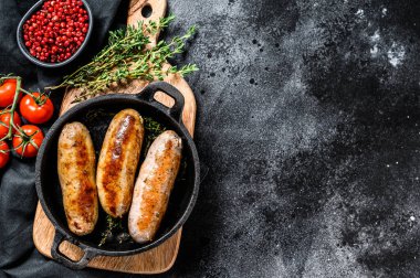 Dökme demir tavada domuz sosisi. Siyah arka plan. Üst Manzara. Boşluğu kopyala.