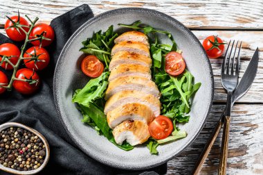 Tavuk göğsü, roka ve domatesli taze salata. Beyaz arka plan. Üst Manzara. Boşluğu kopyala.