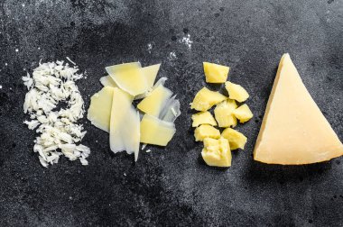 İtalyan sert parmesan peyniri dilimi, kesilmiş, rendelenmiş. Siyah arka plan. Üst görünüm.