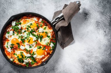 Kızarmış yumurta ve domateslerle kahvaltı. Shakshuka tavada. Geleneksel Türk yemekleri. Gri arka plan. Üst Manzara. Boşluğu kopyala.